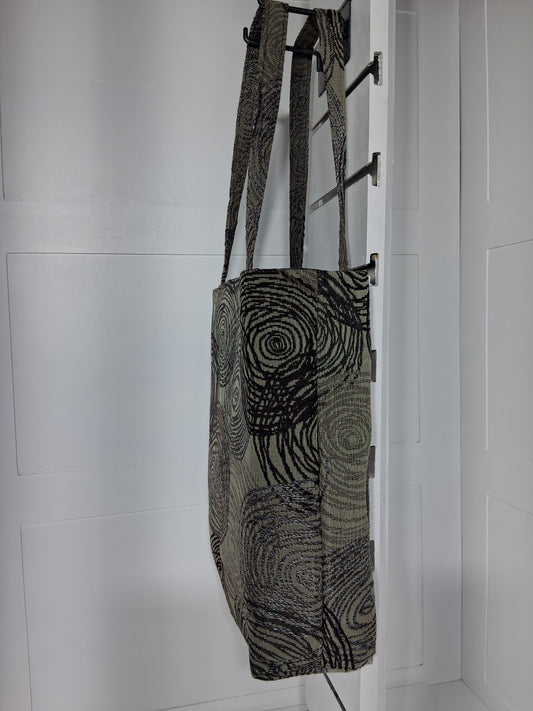Side: "Side view of Pinpins Designs black swirl tapestry tote bag showing structured depth and long shoulder handles"
