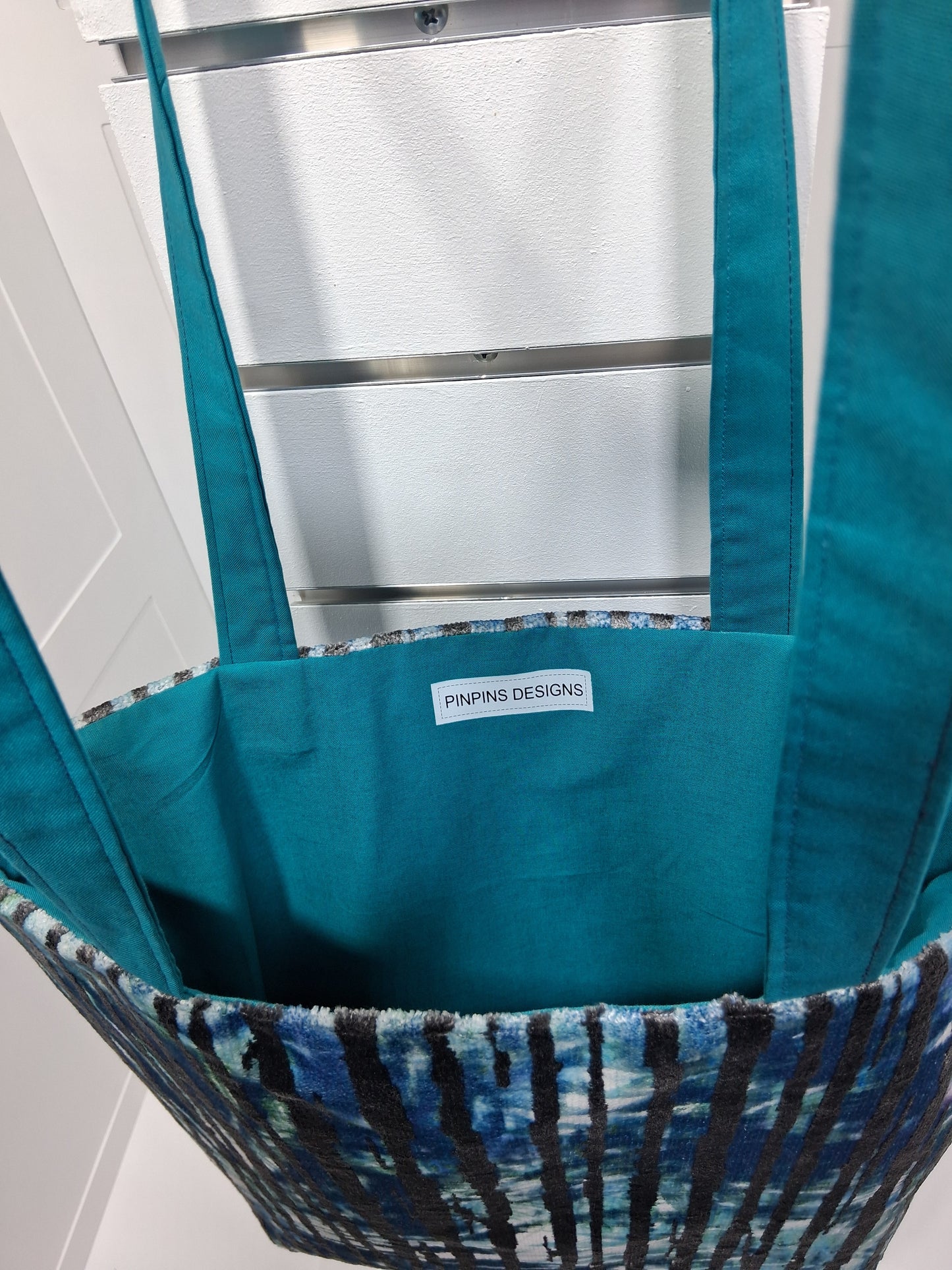 "Pinpins Designs handmade tote bag – interior view showing teal lining and brand label"
