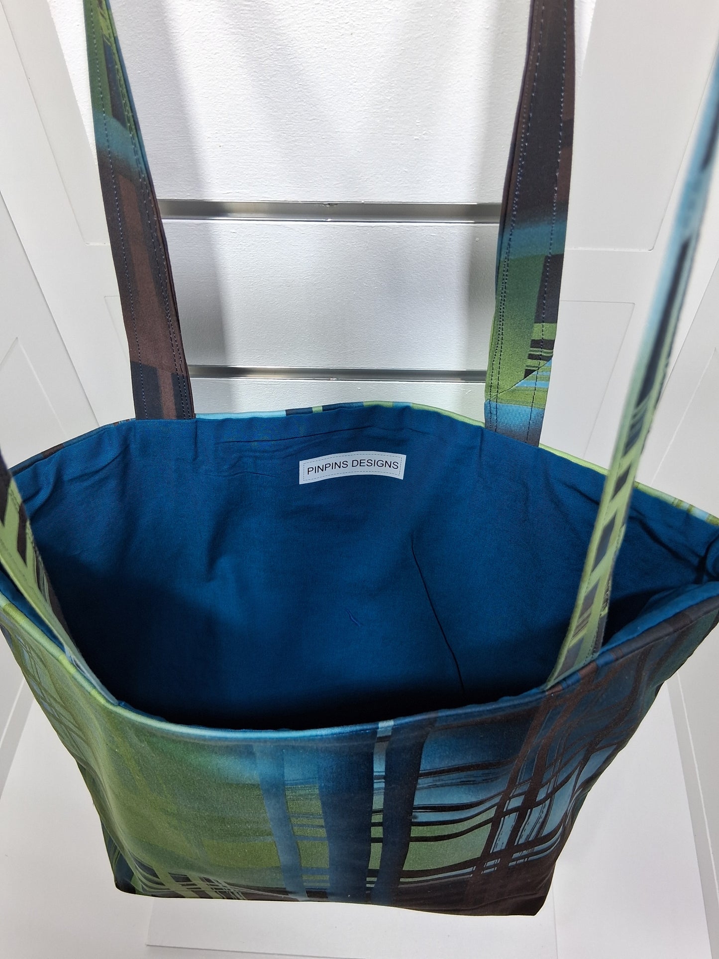"Pinpins Designs handmade tote bag – interior view showing teal blue lining and Pinpins Designs brand label.