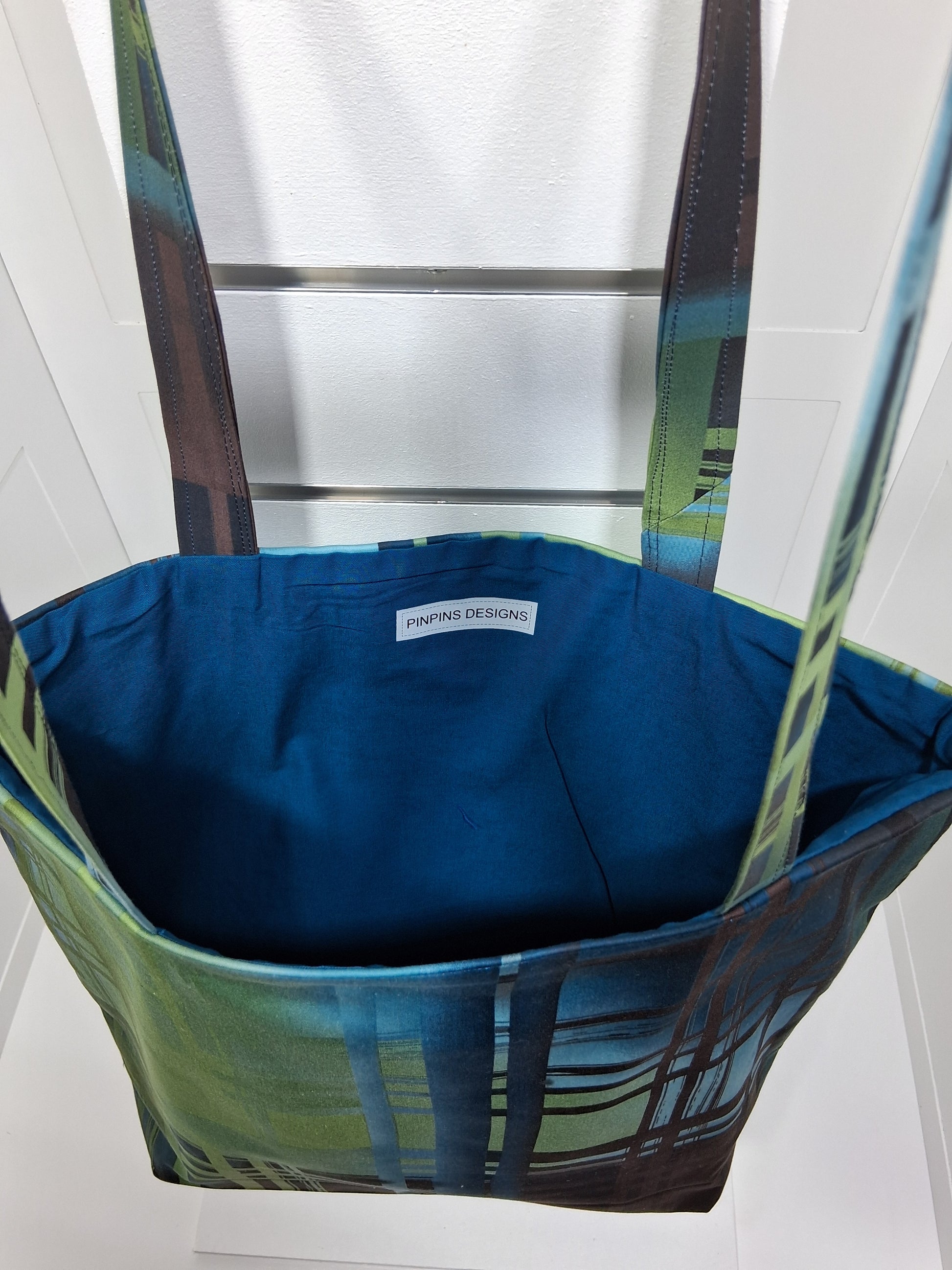 "Pinpins Designs handmade tote bag – interior view showing teal blue lining and Pinpins Designs brand label.