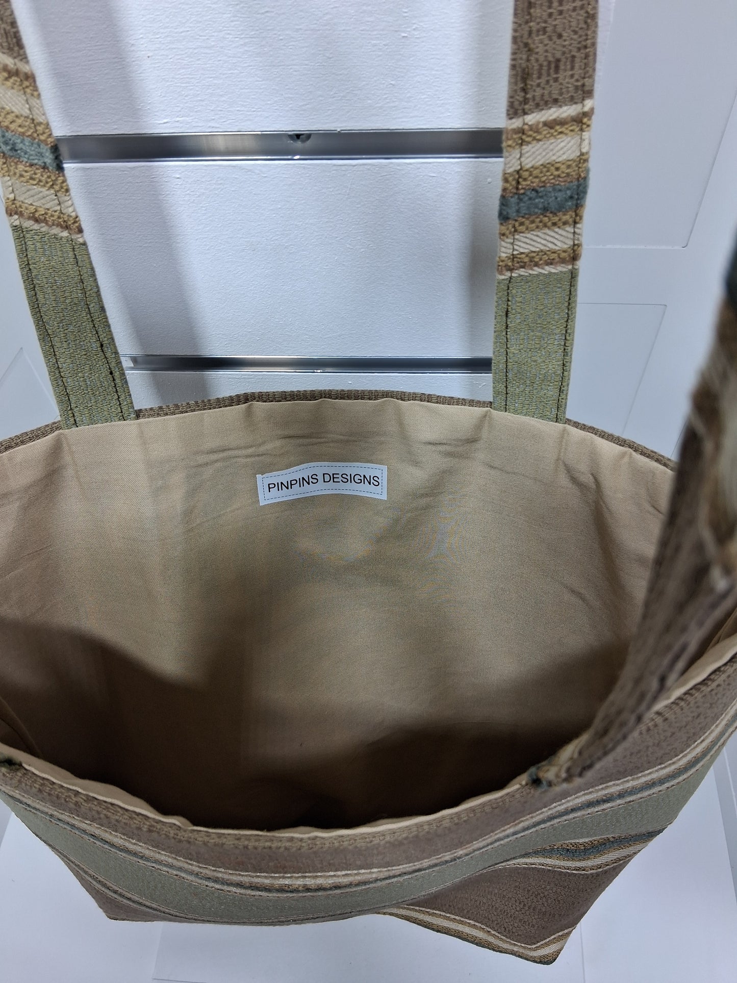 Interior: "Interior view of Pinpins Designs  showing spacious warm beige lining and handmade Pinpins Designs label