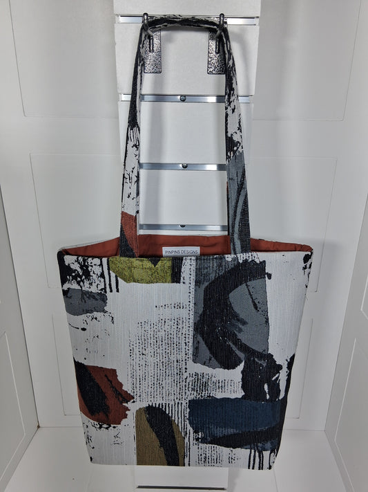 Front: "Handcrafted abstract expressionist tapestry tote bag by Pinpins Designs, front view showing bold black brushstroke pattern with rust and olive accents"