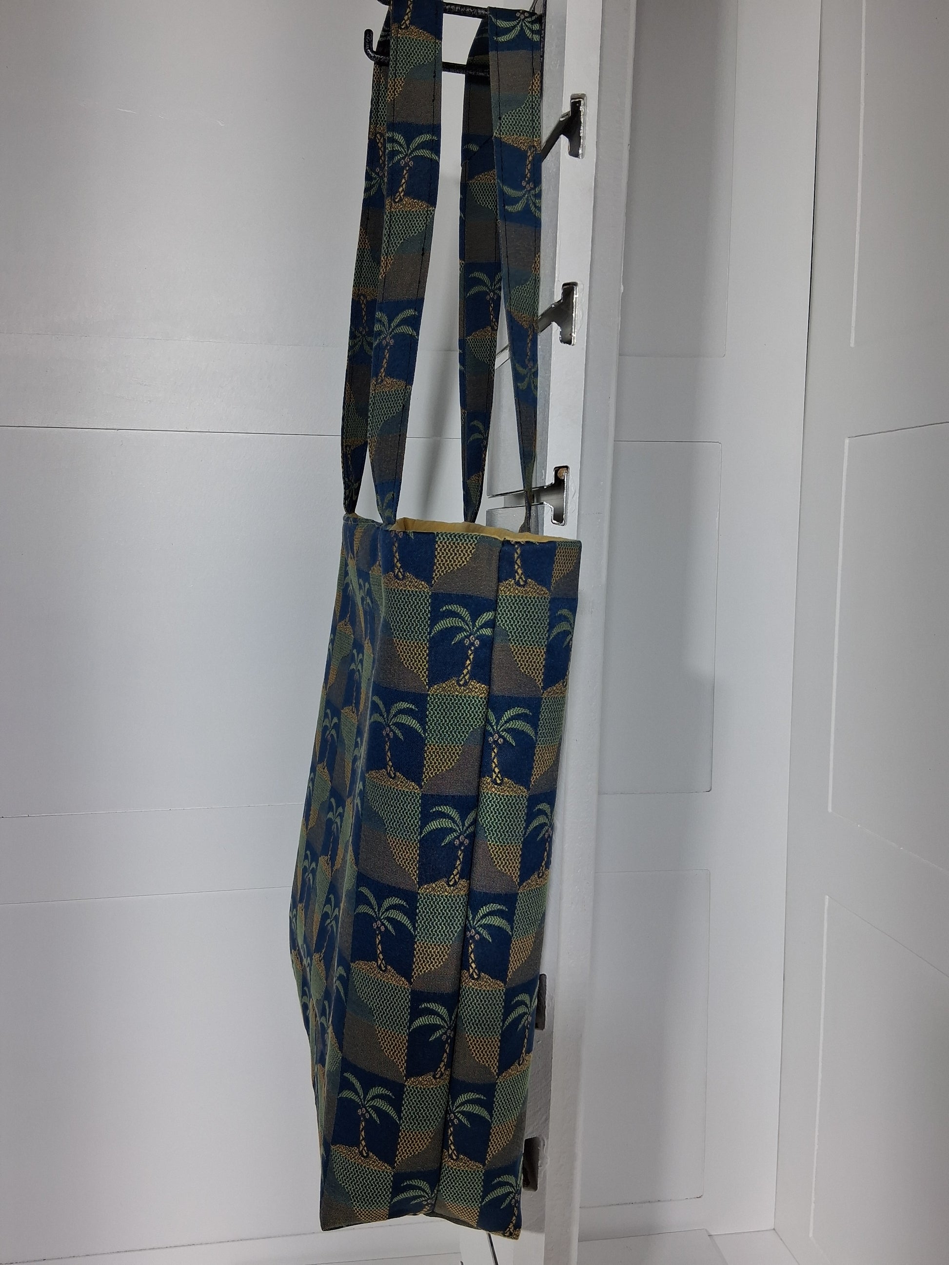 Side: "Side view of Pinpins Designs palm tree tapestry tote bag showing depth and long shoulder handles"