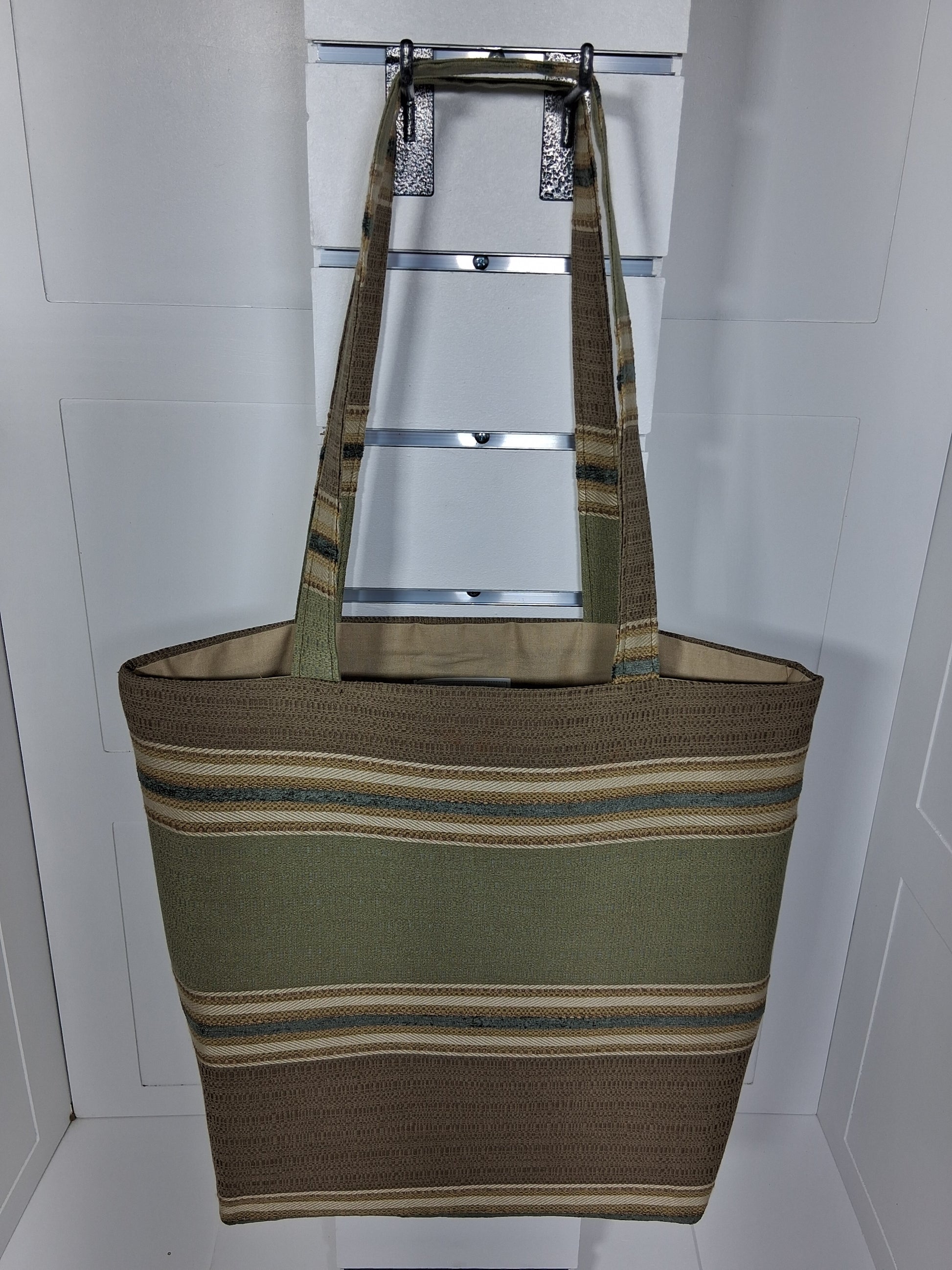 Front: "Handcrafted olive green and tan striped woven tote bag by Pinpins Designs, front view showing structured body and long fabric handles"