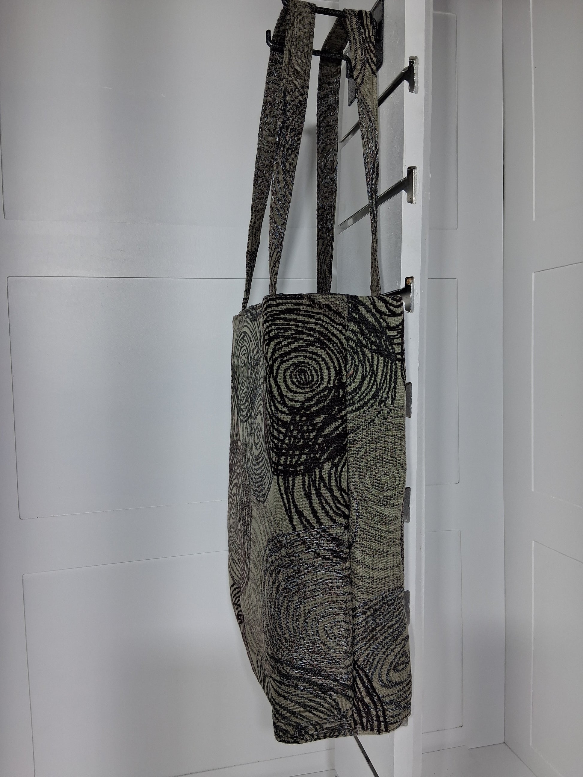 Side: "Side view of Pinpins Designs black swirl tapestry tote bag showing structured depth and long shoulder handles"