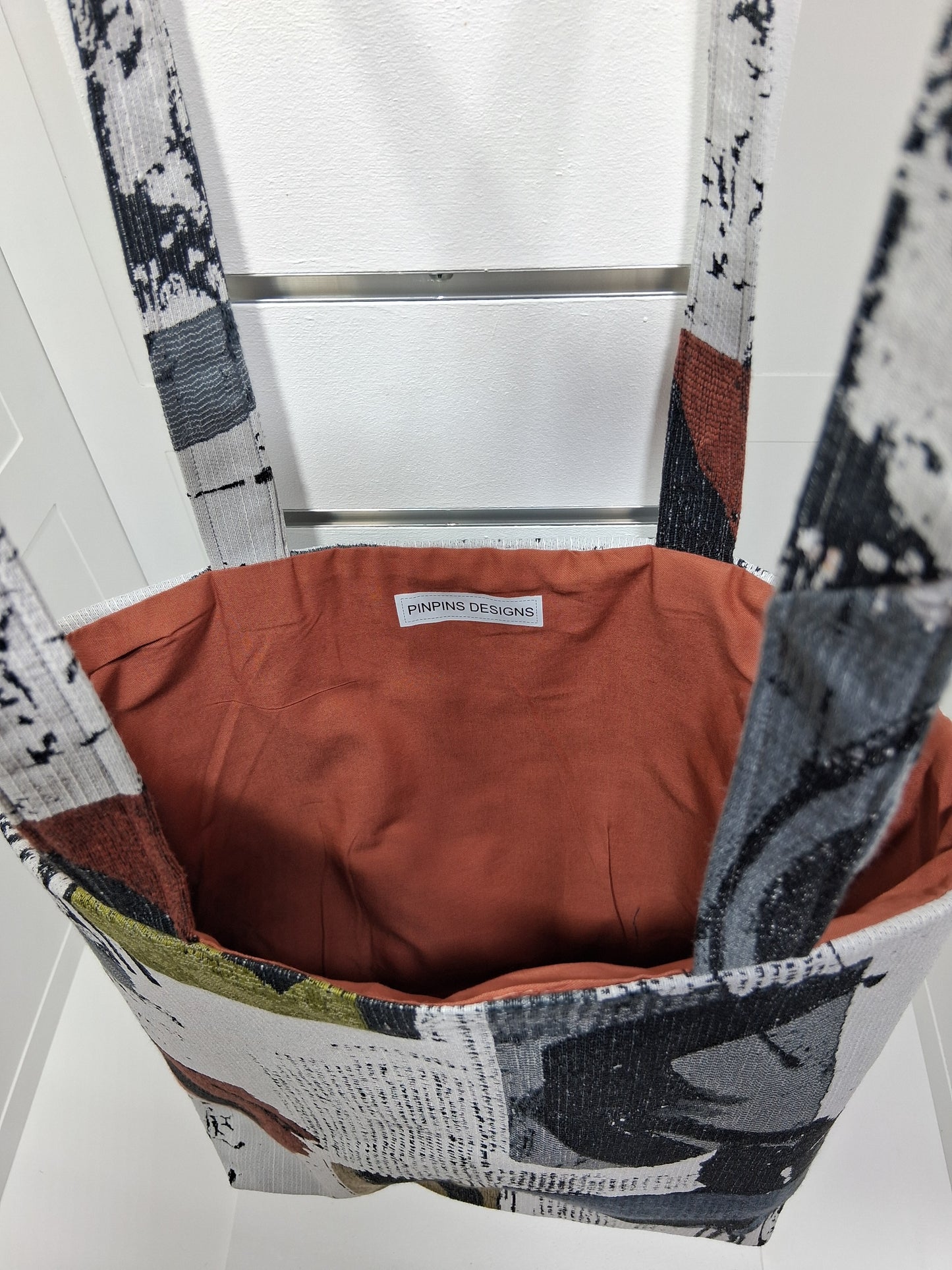 Interior: "Interior view of Pinpins Designs tote bag showing spacious warm terracotta lining and handmade Pinpins Designs label"