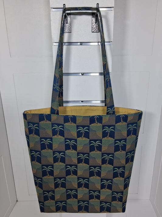 Front: "Handcrafted navy blue and gold palm tree tapestry tote bag by Pinpins Designs, front view showing structured body and long fabric handles"