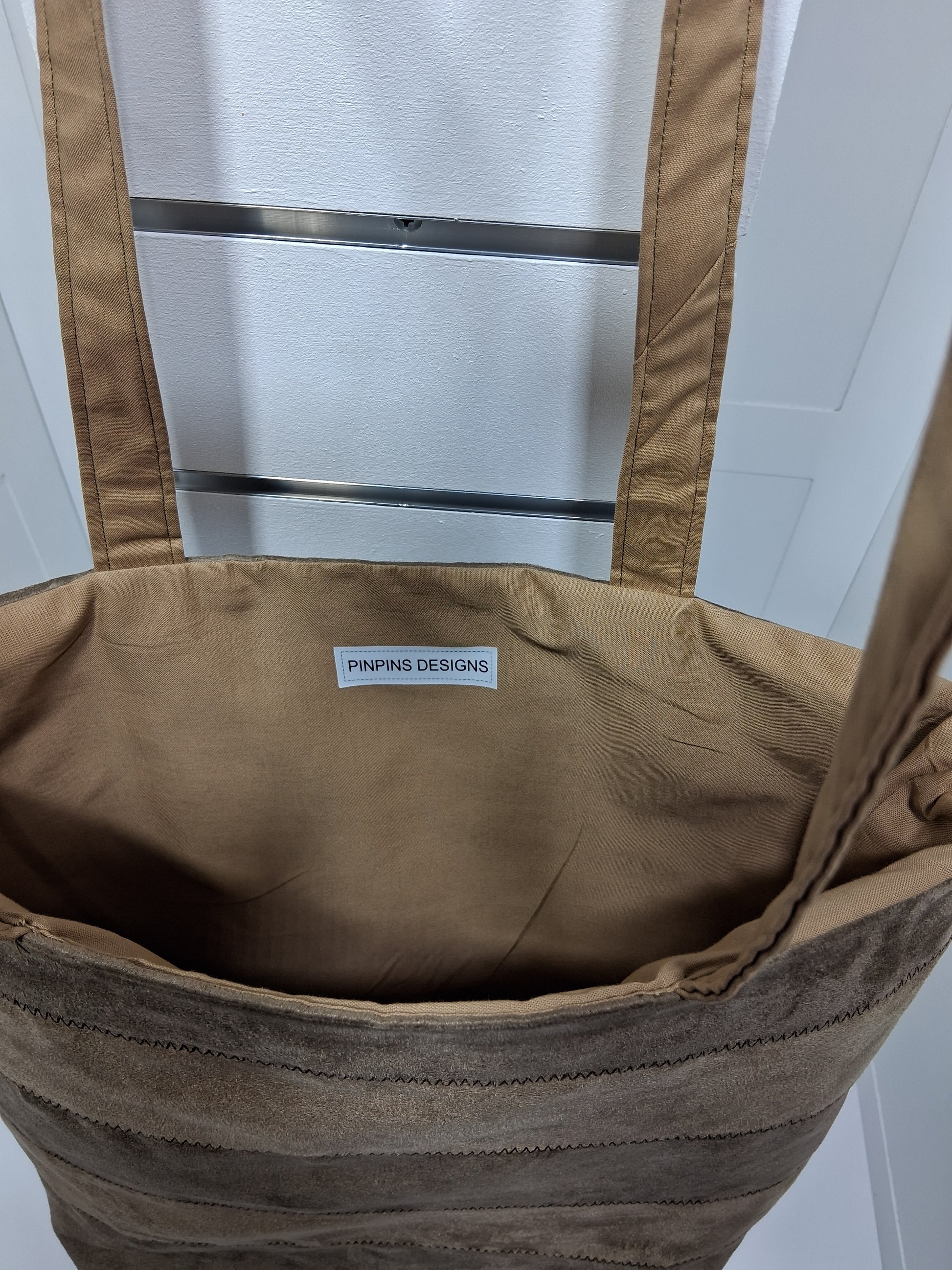 "Pinpins Designs handmade tote bag – interior view showing tan lining and Pinpins Designs brand label"